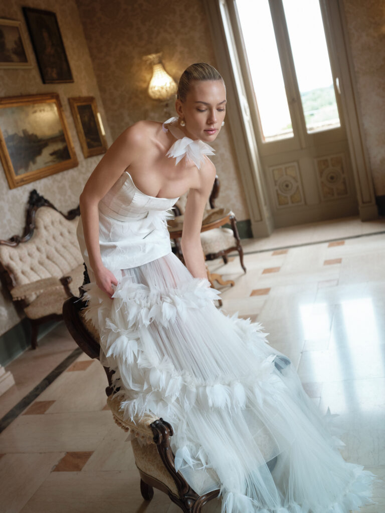 Dolcezza wedding dress shown seated with detachable tulle skirt and floral ruffle detailing