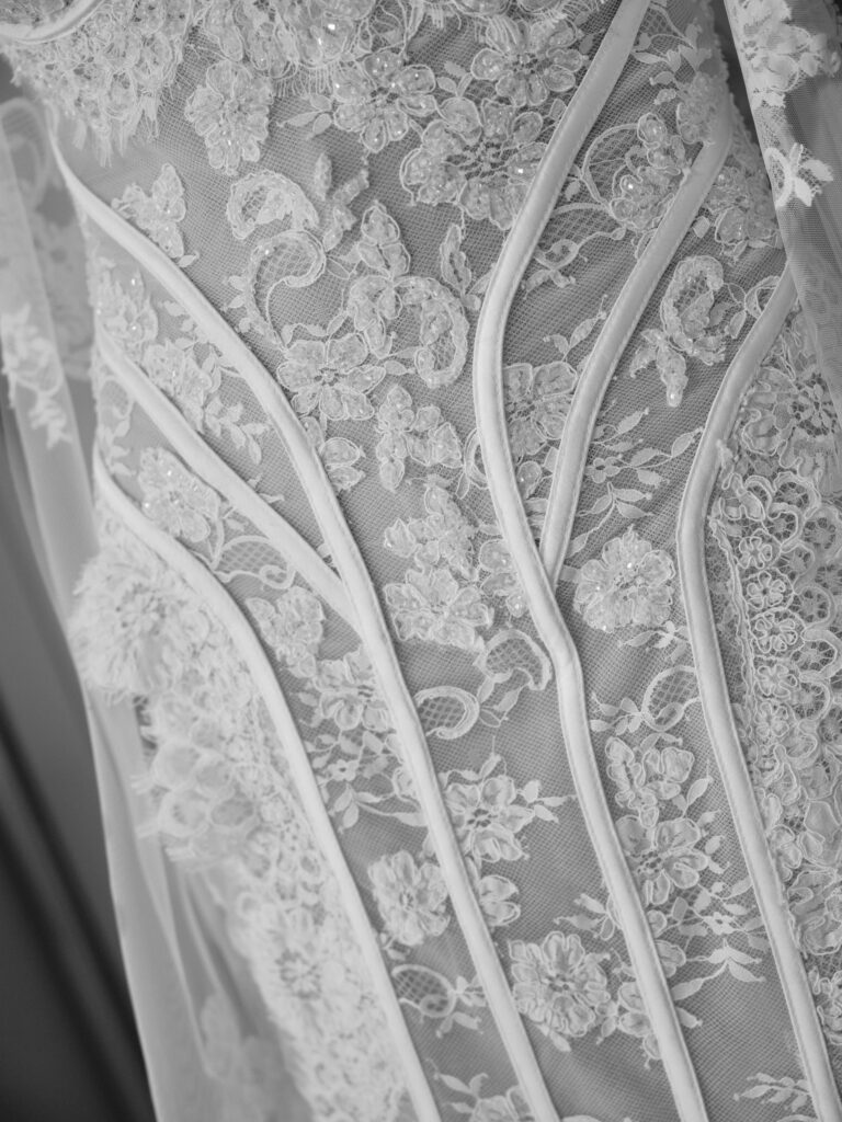 Close-up detail of the Amante wedding dress bodice showing sheer lace, floral appliqué and structured seam lines