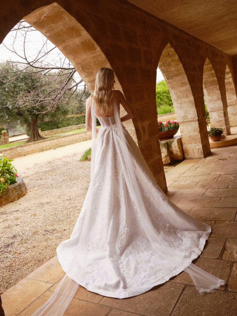Back view of the Mio Cuore wedding dress showing the full ballgown skirt and long sheer draped detail