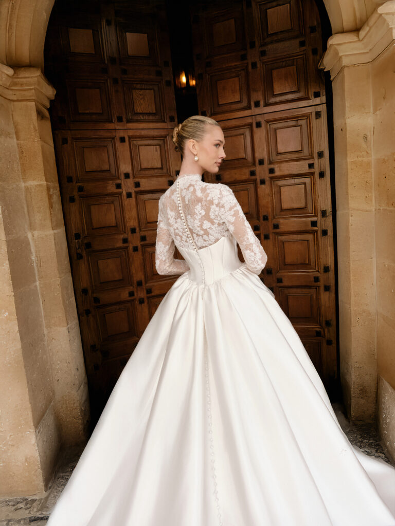 Carissima bridal gown back view showing lace sleeves, structured bodice and full ballgown skirt