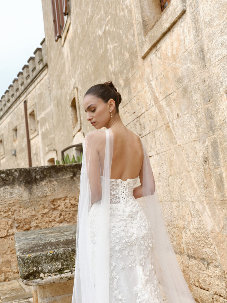 Ti Amo wedding dress back view showing low open back, corset lacing and trailing tulle detail