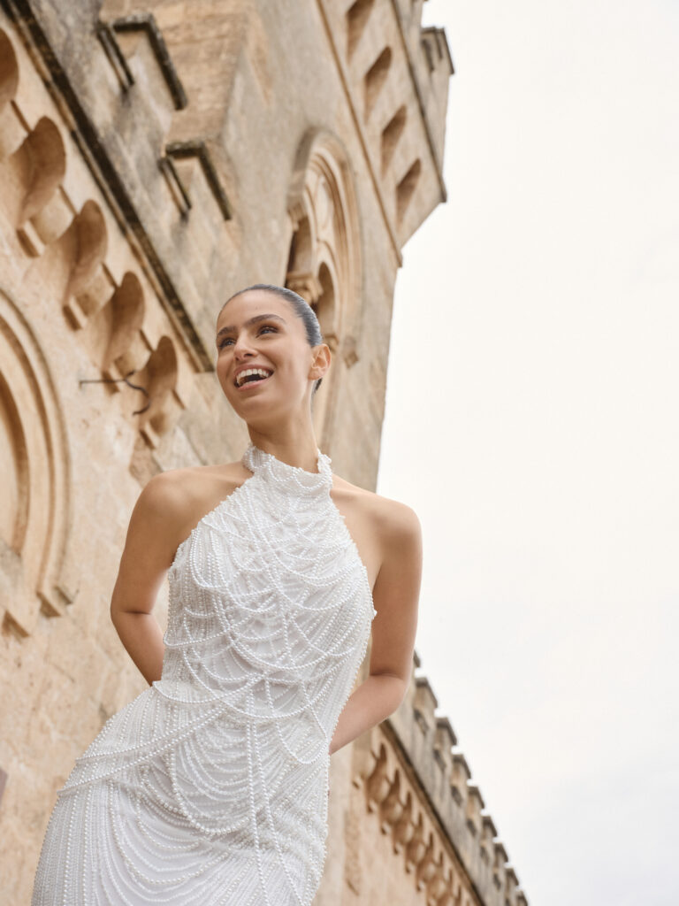 Baci wedding dress angled front view showing sculpted fit and cascading pearl beading