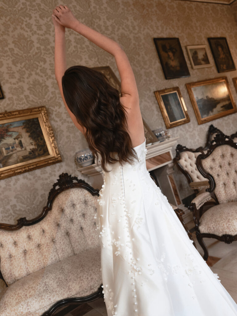 Mia Sposa wedding dress back view showing warm ivory skirt, floral petal detail and flowing train