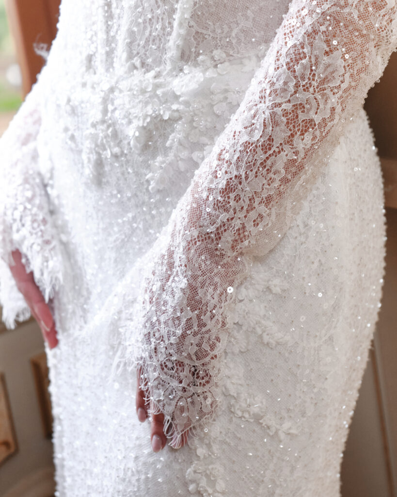 Un Abbraccio bridal gown close-up showing embellished bodice and sheer beaded sleeves